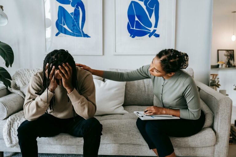 A couple sharing a moment of support and understanding on a living room sofa, depicting comfort.